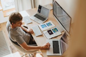 A man working on laptop and desktop from home