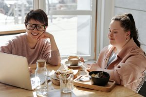 Happy young women with disability and woman watching on a laptop