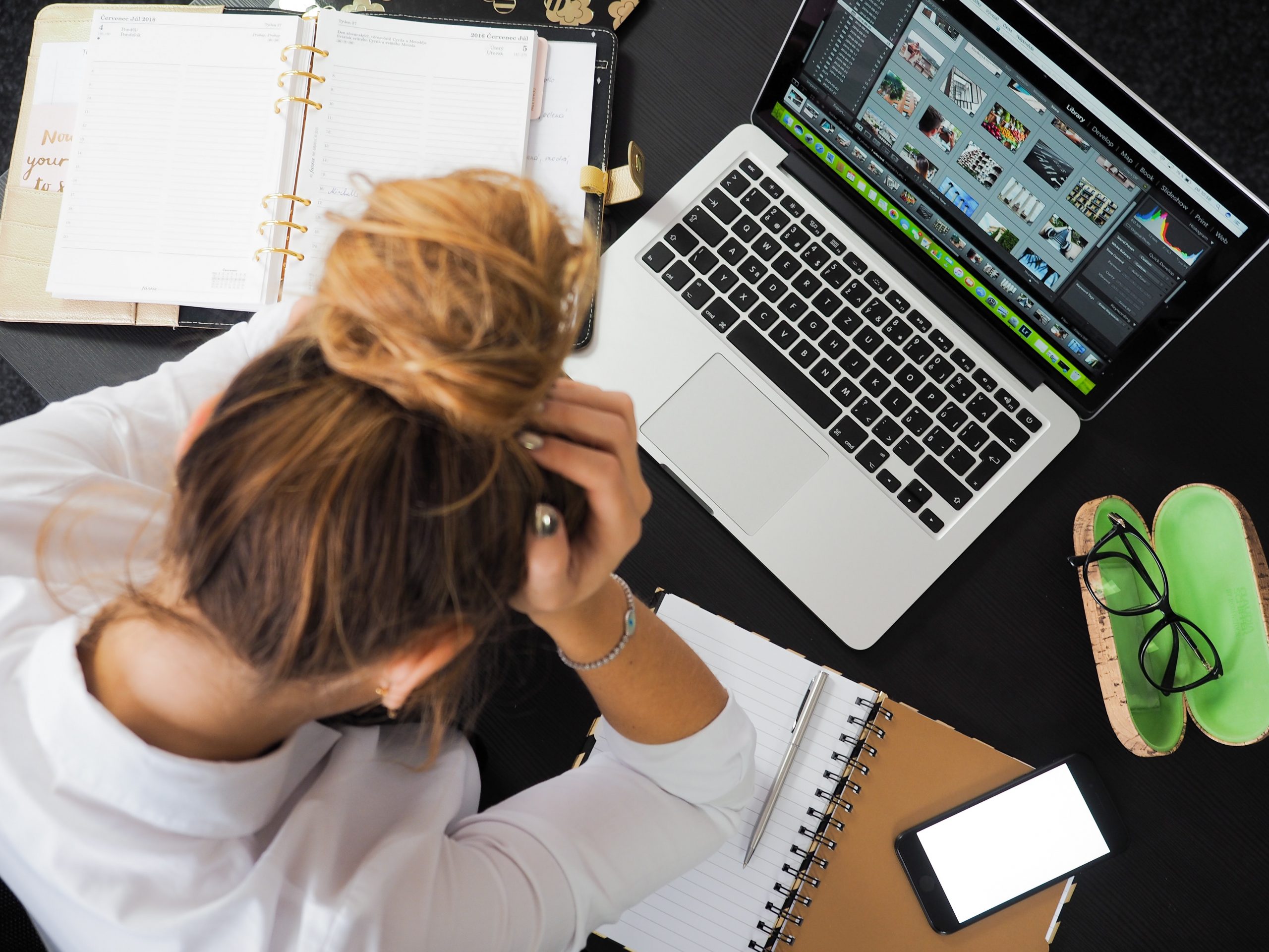 woman sitting in front of a laptop holding her head