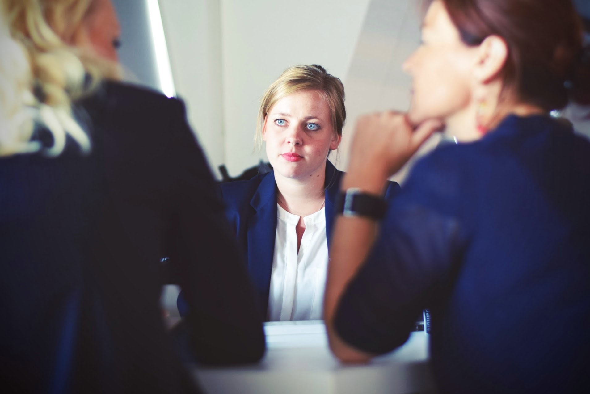 three business women sitting beside table