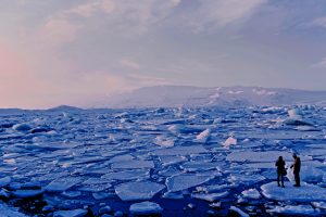 man and woman standing on broken ice in arctic