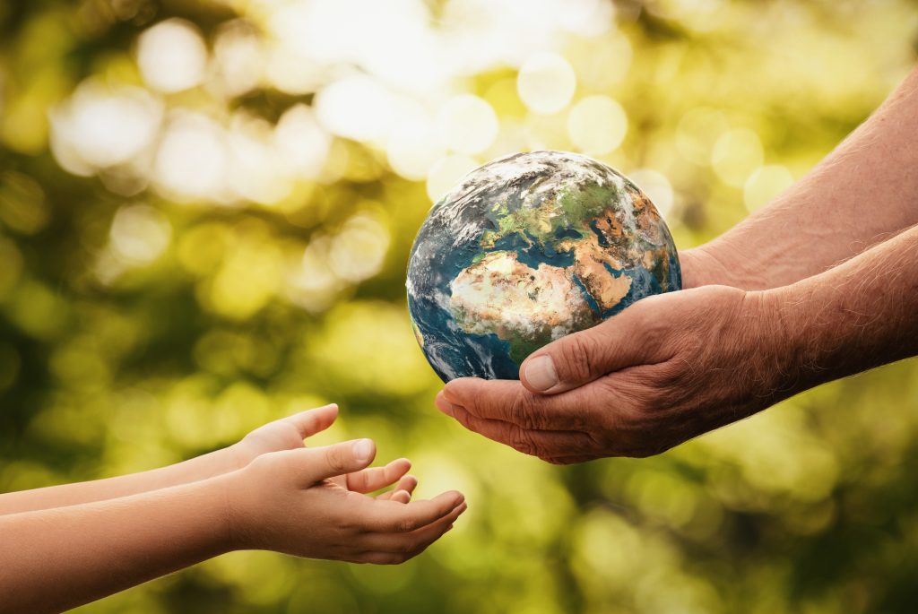 Close up of senior hands giving small planet earth to a child 