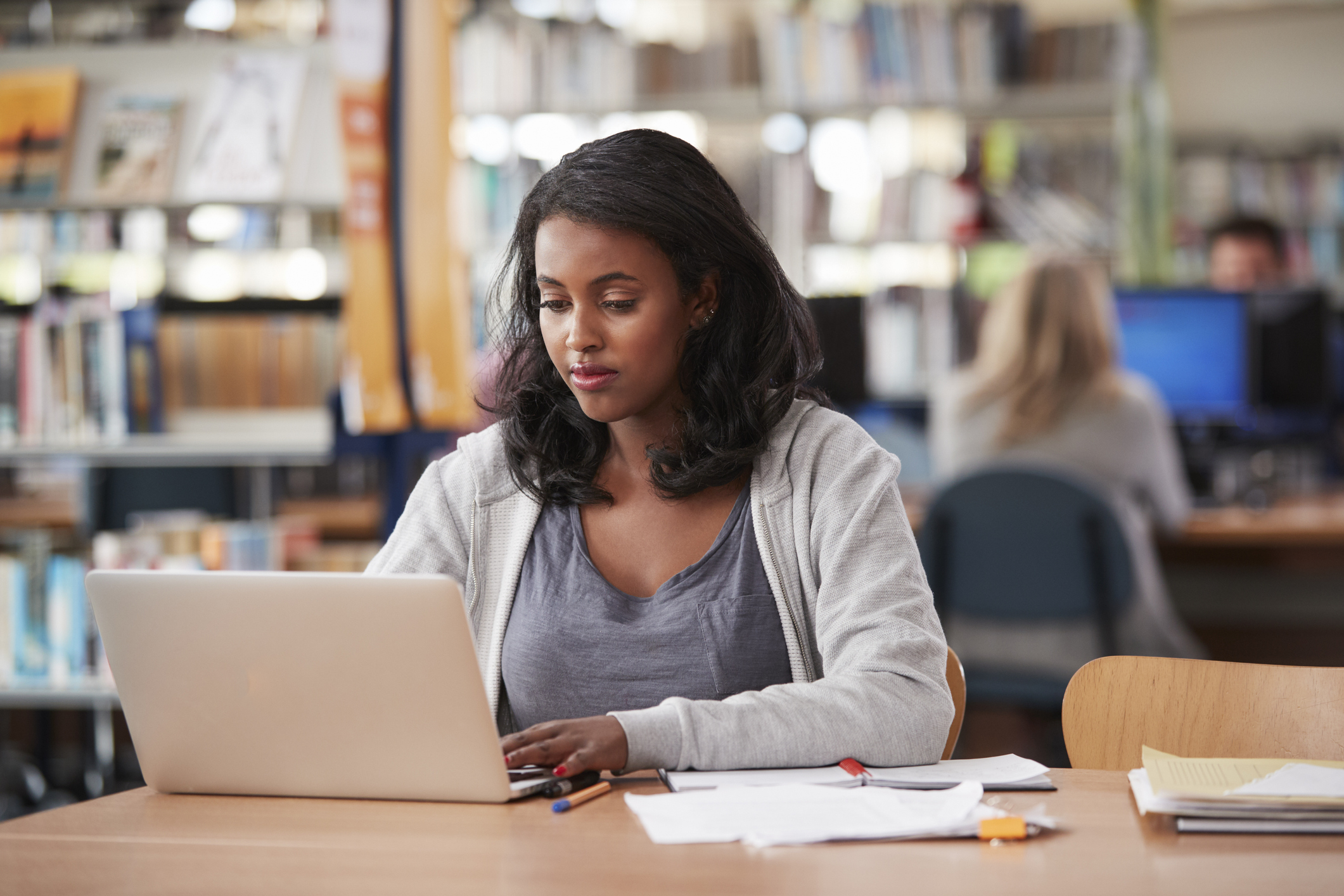 Female Student Working On Laptop In College Library