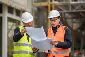 apprentice at work on construction site with senior engineer.