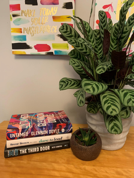 stack of books beside plant on wooden table