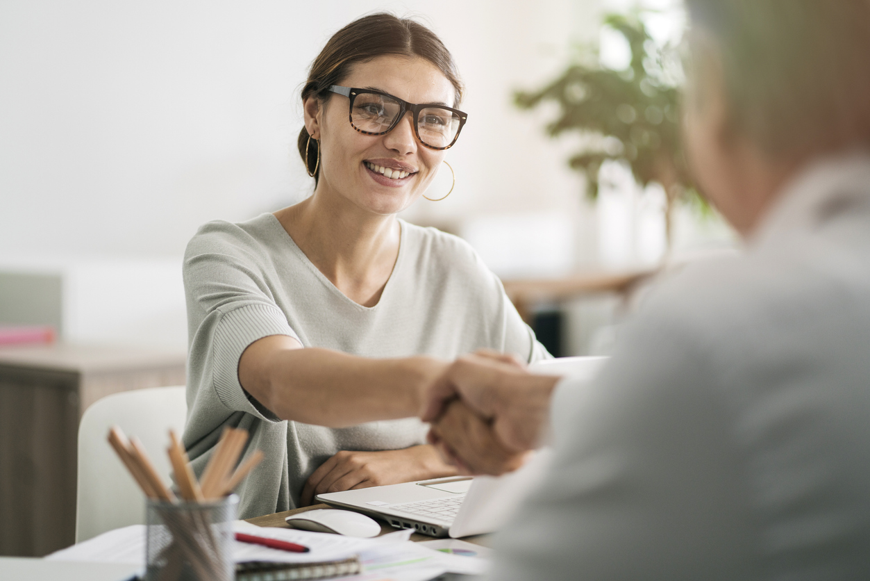 woman and man shaking hands across desk