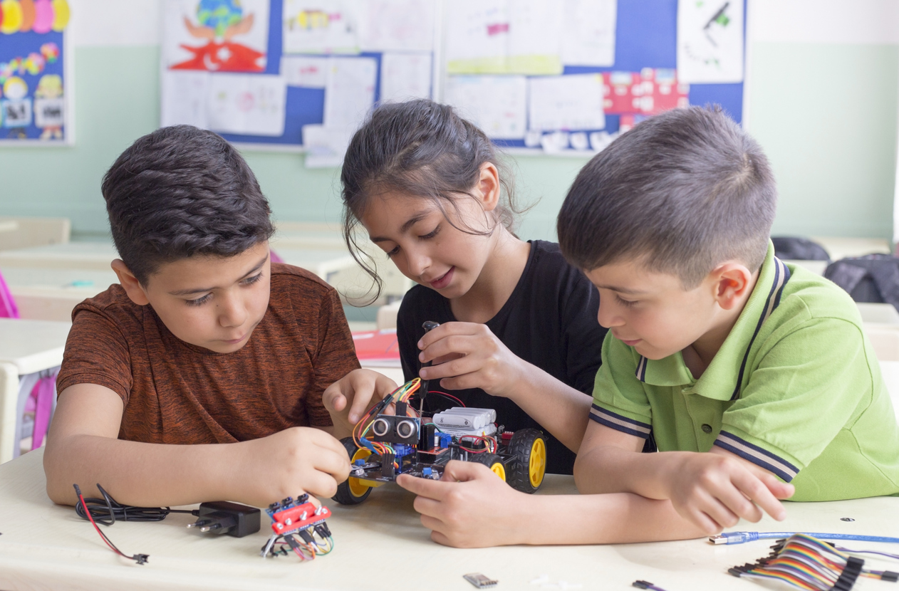 three students building robot in class