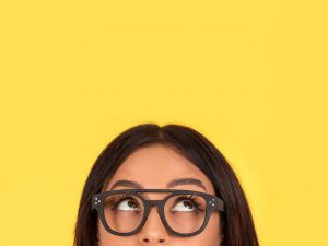 woman looking up thinking on yellow background