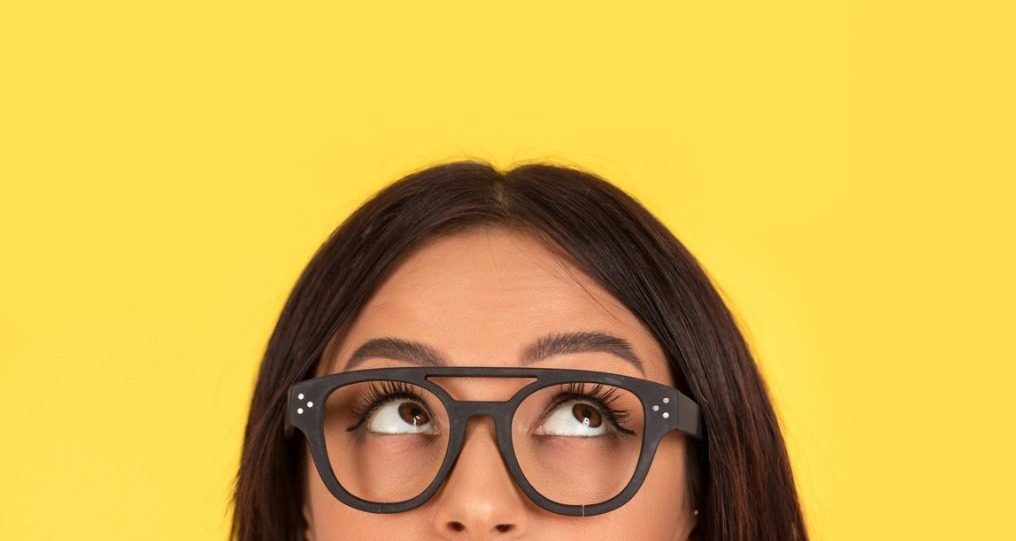 woman looking up thinking on yellow background