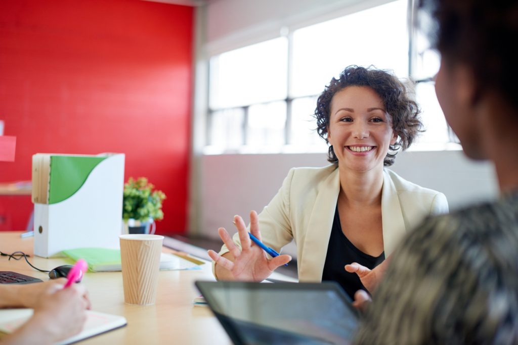 woman smiling and speaking to other people in office