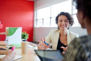 woman smiling and speaking to other people in office