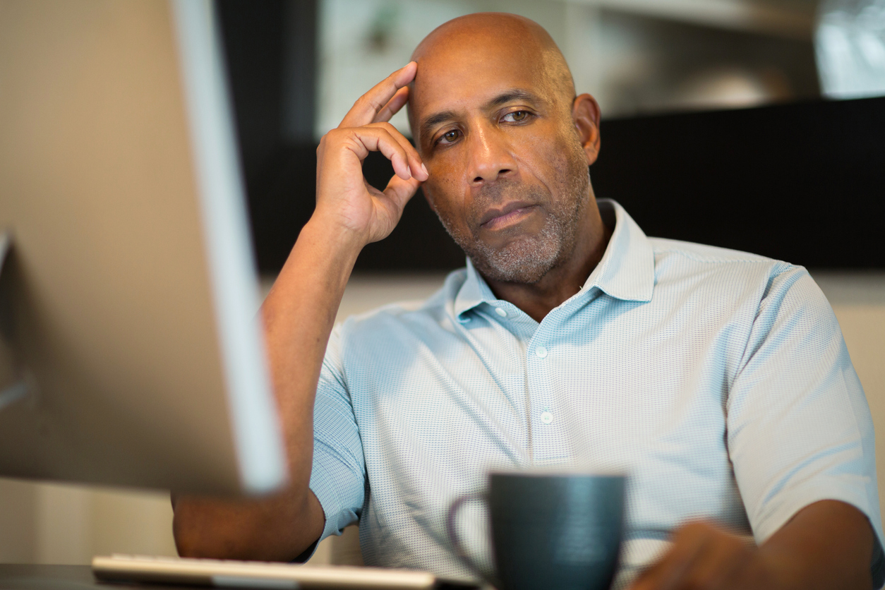 black man looking unhappy at desk at work