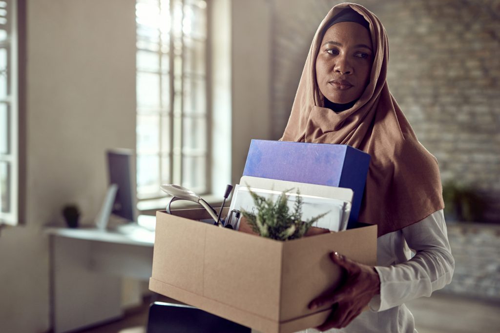 woman wearing hijab carries personal belongings out of office