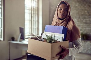woman wearing hijab carries personal belongings out of office