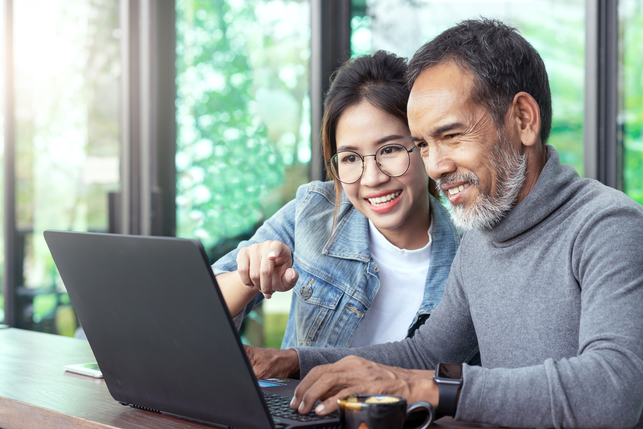 young woman helping older man using computer