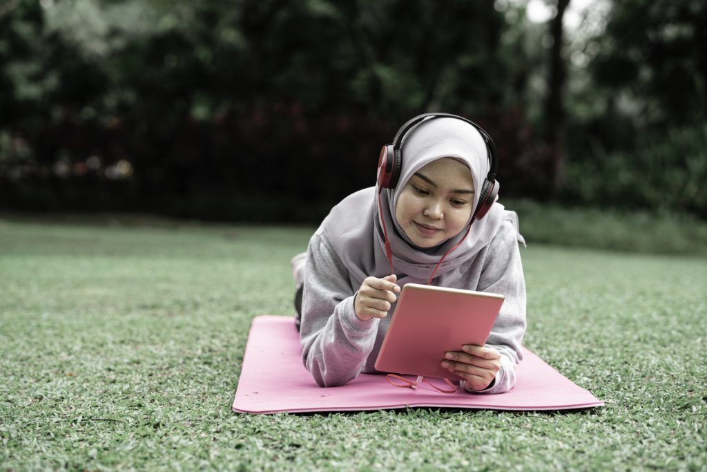 muslim teen girl using tablet in park