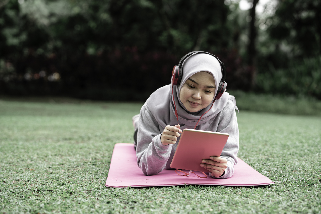 muslim teen girl using tablet in park