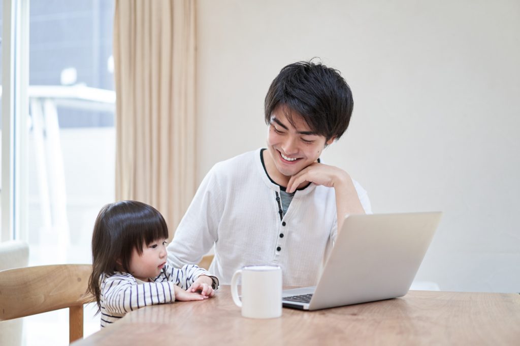 dad working on computer with young daughter beside him