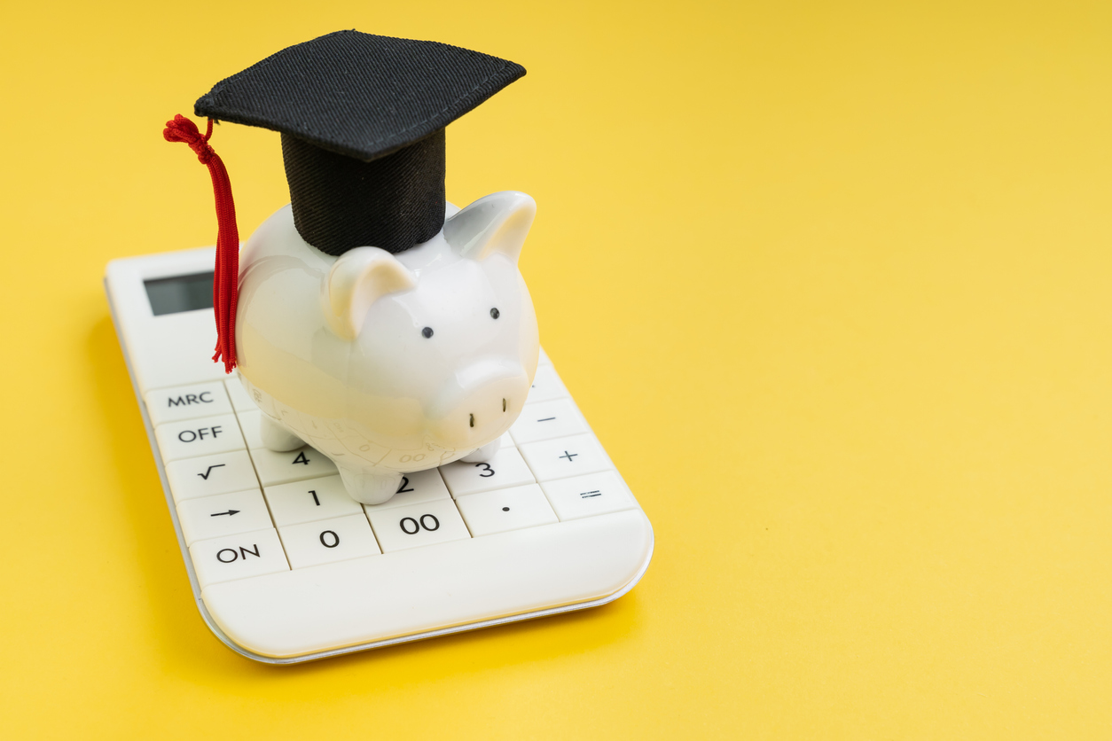 piggy bank wearing graduation cap sitting on top of calculator