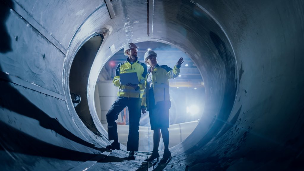 two engineers walking inside large pipe