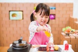 Little girl playing in toy kitchen.