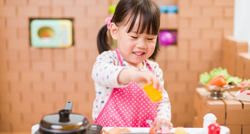 Little girl playing in toy kitchen.