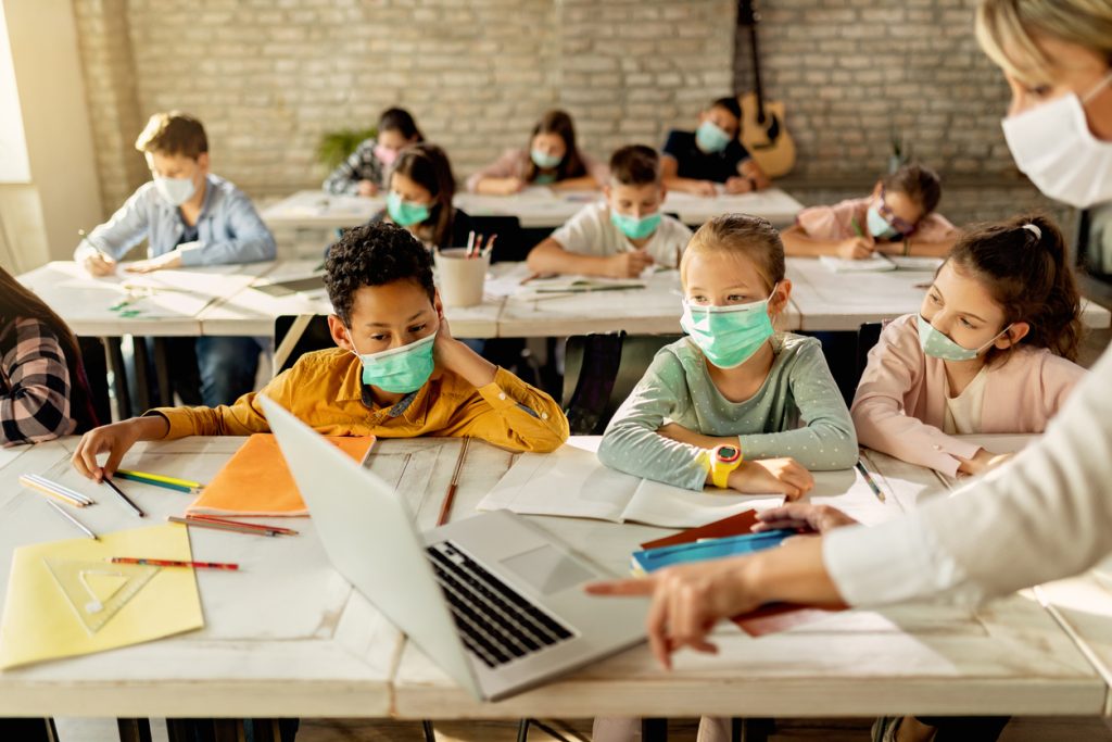 Young kids wearing masks sitting in classroom