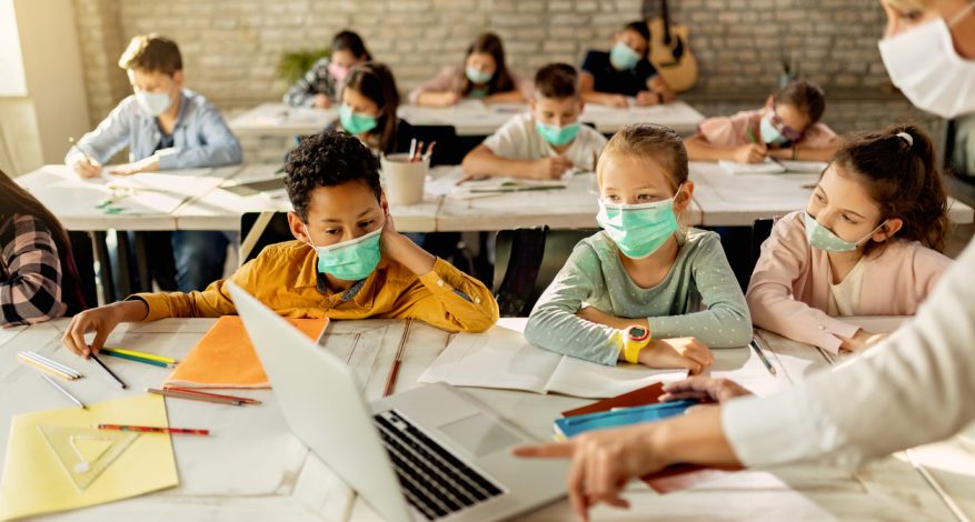 Young kids wearing masks sitting in classroom