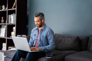 Man sitting on couch typing on computer