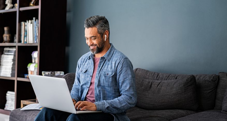 Man sitting on couch typing on computer