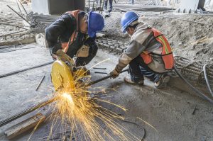 Heat sparks fly out in construction site due to two men using grinding machine