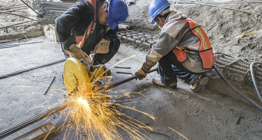 Heat sparks fly out in construction site due to two men using grinding machine