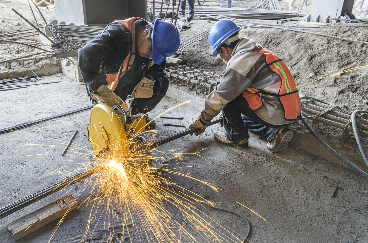 Heat sparks fly out in construction site due to two men using grinding machine