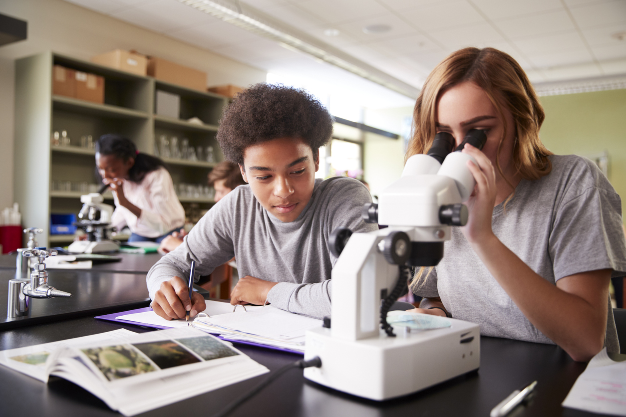 Two high school students looking through microscope in class