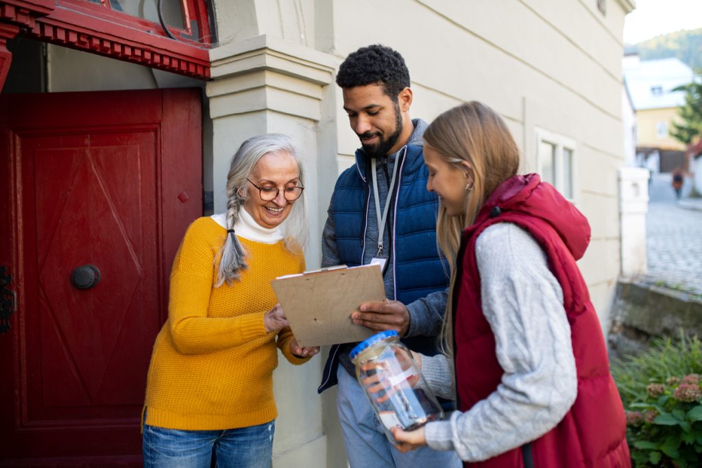 Volunteers doing door-to-door survey with woman
