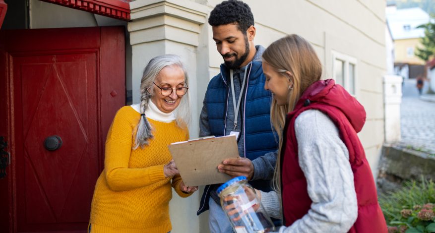 Volunteers doing door-to-door survey with woman