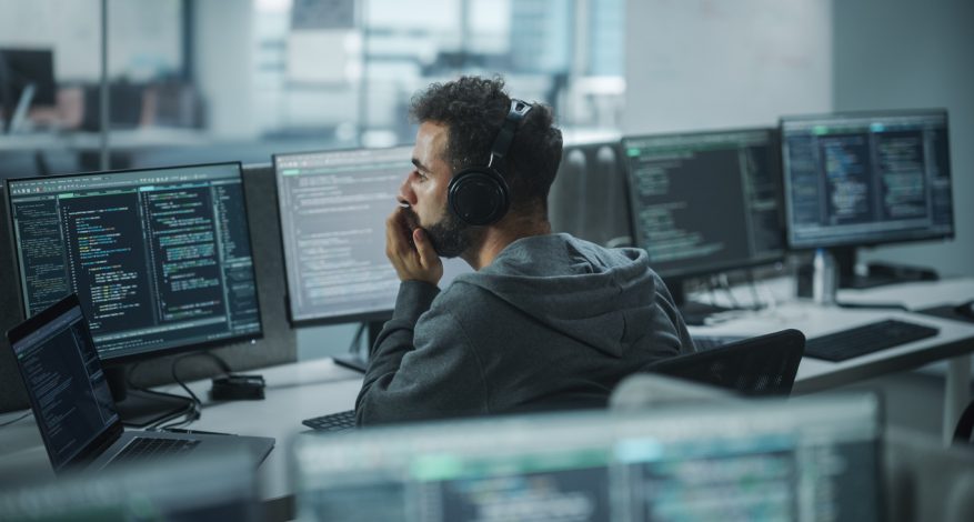 IT programmer looking at code on computer in office