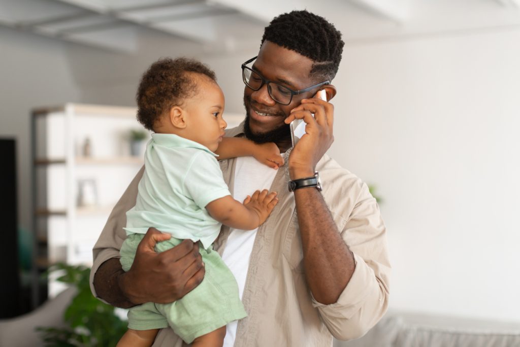 Dad holding baby while talking on phone
