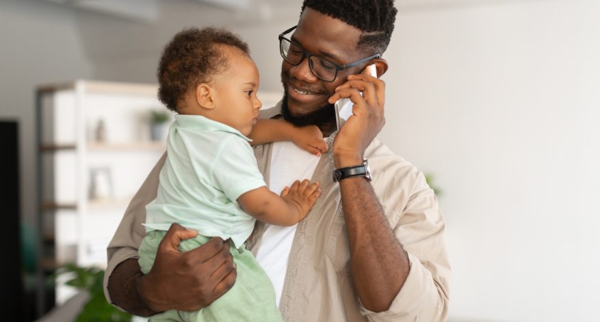 Dad holding baby while talking on phone